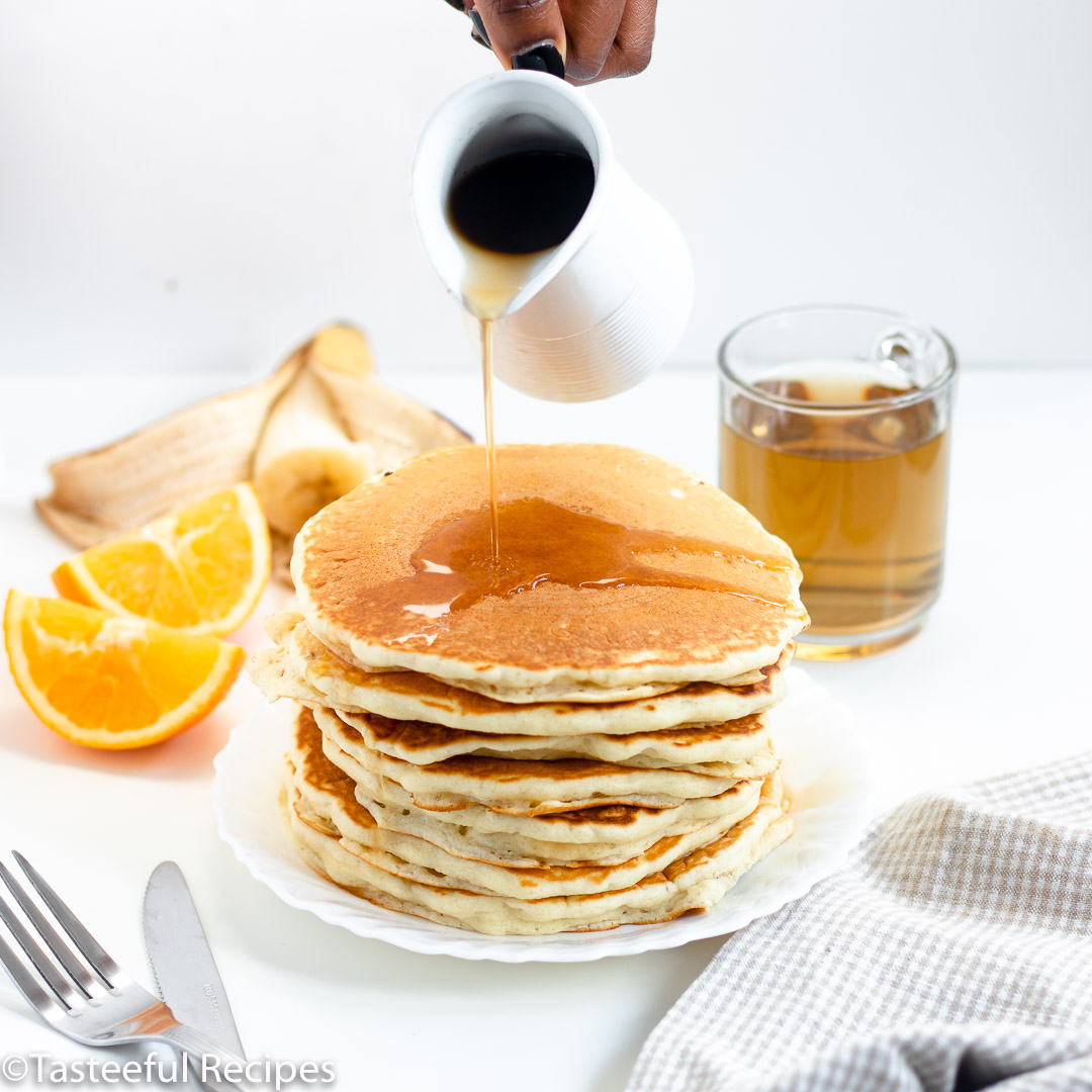 Straight on shot of buttermilk pancakes being drizzled with syrup