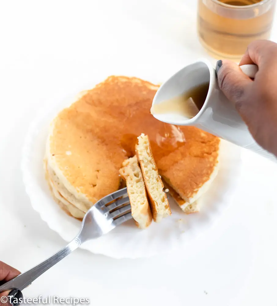 Overhead shot of pancakes being drizzled with pancake syrup