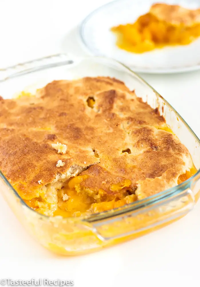 Angled shot of a coconut mango cobbler in a a clear glass baking dish